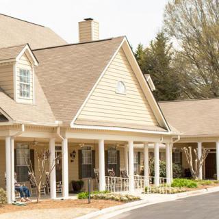A charming residential home with a spacious porch and surrounding trees.