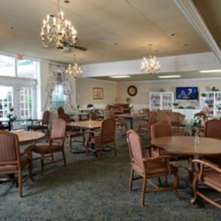 A cozy dining area with tables, chairs, chandeliers, and a television.