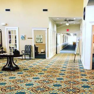 A spacious lobby with patterned carpet leading to a hallway.