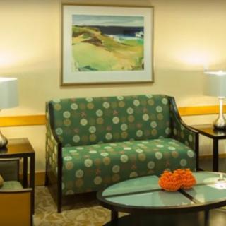 A cozy living room with a patterned sofa, artwork on the wall, and table lamps providing warm lighting.