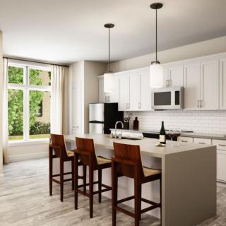 A modern kitchen featuring white cabinets, an island with bar stools, and elegant pendant lighting.