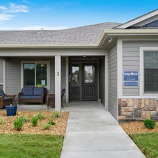 A modern residential house with a front porch and well-maintained lawn.