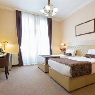 A cozy hotel room with twin beds, a desk, and elegant decor.