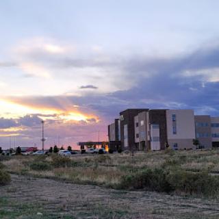 A serene sunset casting a warm glow over a building in an open landscape.