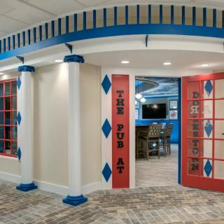 A creatively designed interior space featuring decorative columns and a vibrant color scheme, leading into a gaming area.