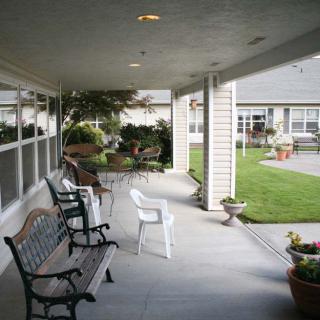 A peaceful veranda with benches and chairs overlooking a garden.