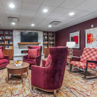 A cozy living room with plush armchairs, a fireplace, and a well-stocked bookshelf.