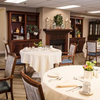 An elegant dining room interior with round tables and wooden chairs, set for a meal.