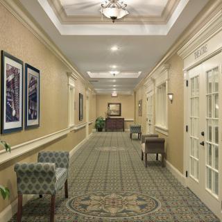 A well-lit hotel hallway with elegant decor and seating areas along the sides.