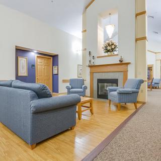 A cozy living room with blue sofas and chairs surrounding a fireplace.