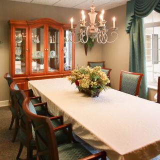 A well-decorated dining room featuring a long table with chairs, a chandelier, and a china cabinet.