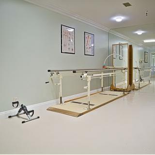 A rehabilitation therapy room featuring parallel bars and exercise equipment for patient recovery.