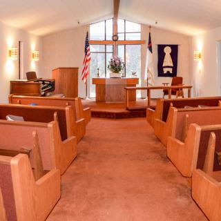 Interior view of a church with wooden pews and an altar at the front.