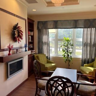 A cozy living room corner with green chairs and a view through large windows.