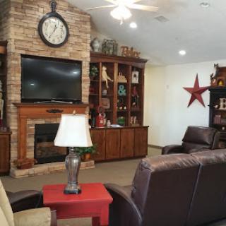 A cozy living room featuring a stone fireplace, built-in bookshelf, and comfortable seating arrangements.
