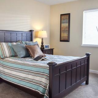 A cozy bedroom with a striped bedspread and wooden furniture.