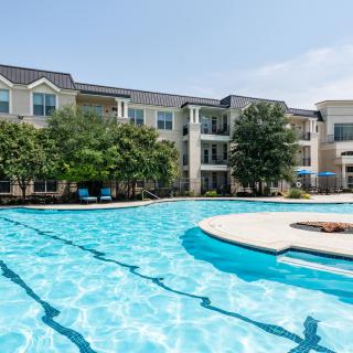 A sunny day at a modern apartment complex with a large outdoor swimming pool.