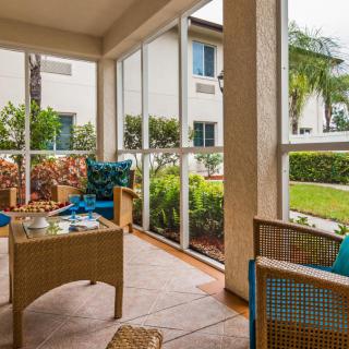 A cozy screened patio with comfortable seating and lush greenery.