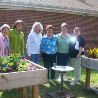 A group of people standing together in a garden with raised beds.