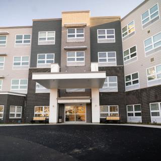 A modern multi-story apartment building with a central entrance.