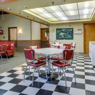 A retro-style diner interior with red chairs and a black-and-white checkered floor.