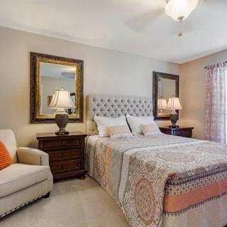 A cozy bedroom with elegant decor, featuring a plush bed, stylish armchair, and warm lighting.