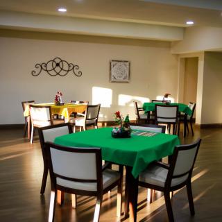 A dining area with tables covered in green tablecloths and arranged neatly.