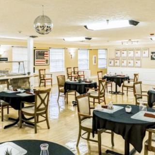 A well-lit dining area with neatly arranged tables and chairs, featuring simple decor.