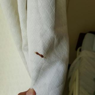 A white curtain with a noticeable hole in it.