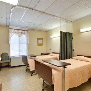 A view of a hospital patient room equipped with two beds and privacy curtains.