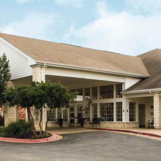 The image shows a building with a covered entrance and landscaped surroundings.
