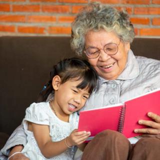 A grandmother and her granddaughter enjoy reading a book together, sharing a joyful moment.
