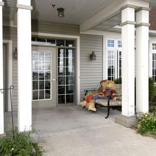 A cozy porch with a bench and decorative columns at the entrance of a building.