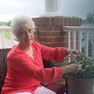 An elderly woman enjoying her time gardening on the porch.