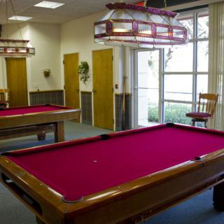 A recreational game room featuring two billiard tables with red felt.