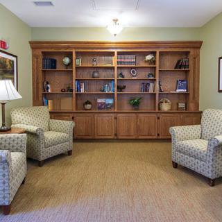 A cozy living room with armchairs and a wooden bookshelf.