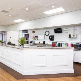 Modern reception area with a large white counter and office supplies.