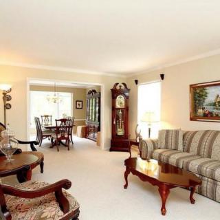 A traditional living room with classic furniture and a view into the dining area.