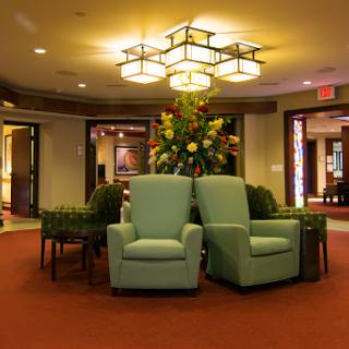 A cozy lobby area featuring comfortable chairs, elegant lighting, and decorative floral arrangements.