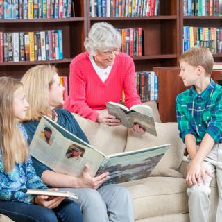 A multigenerational family enjoying reading together in a library setting.
