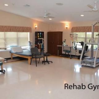 A well-equipped rehabilitation gym with exercise machines and therapy tables.