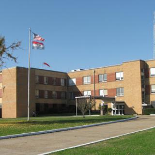 A view of a brick educational institution with flags waving in front.