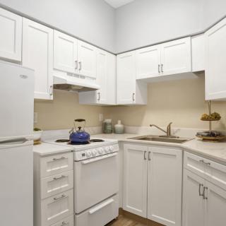 A modern kitchen with white cabinets and standard appliances.