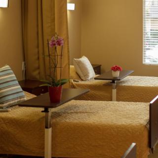 A hospital room with two neatly arranged beds and bedside tables.