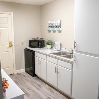 A minimalist kitchen with white cabinets, a microwave, fridge, and decorative elements.
