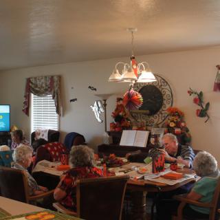 A group of seniors gathered in a decorated living room, engaging in conversation.