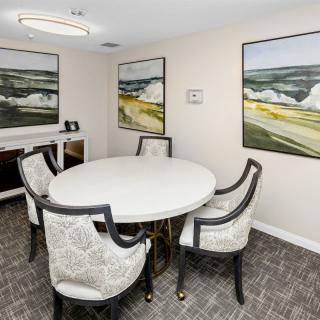A small, elegantly furnished meeting room with a round table and four chairs, adorned with landscape paintings on the walls.
