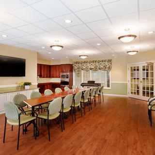 A modern conference room with a large table, seating, and a television.