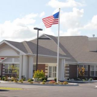 A suburban building with an American flag flying on a flagpole against a cloudy sky.