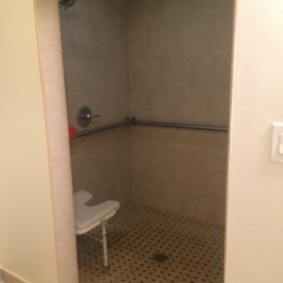 An accessible shower with a safety bar and chair.